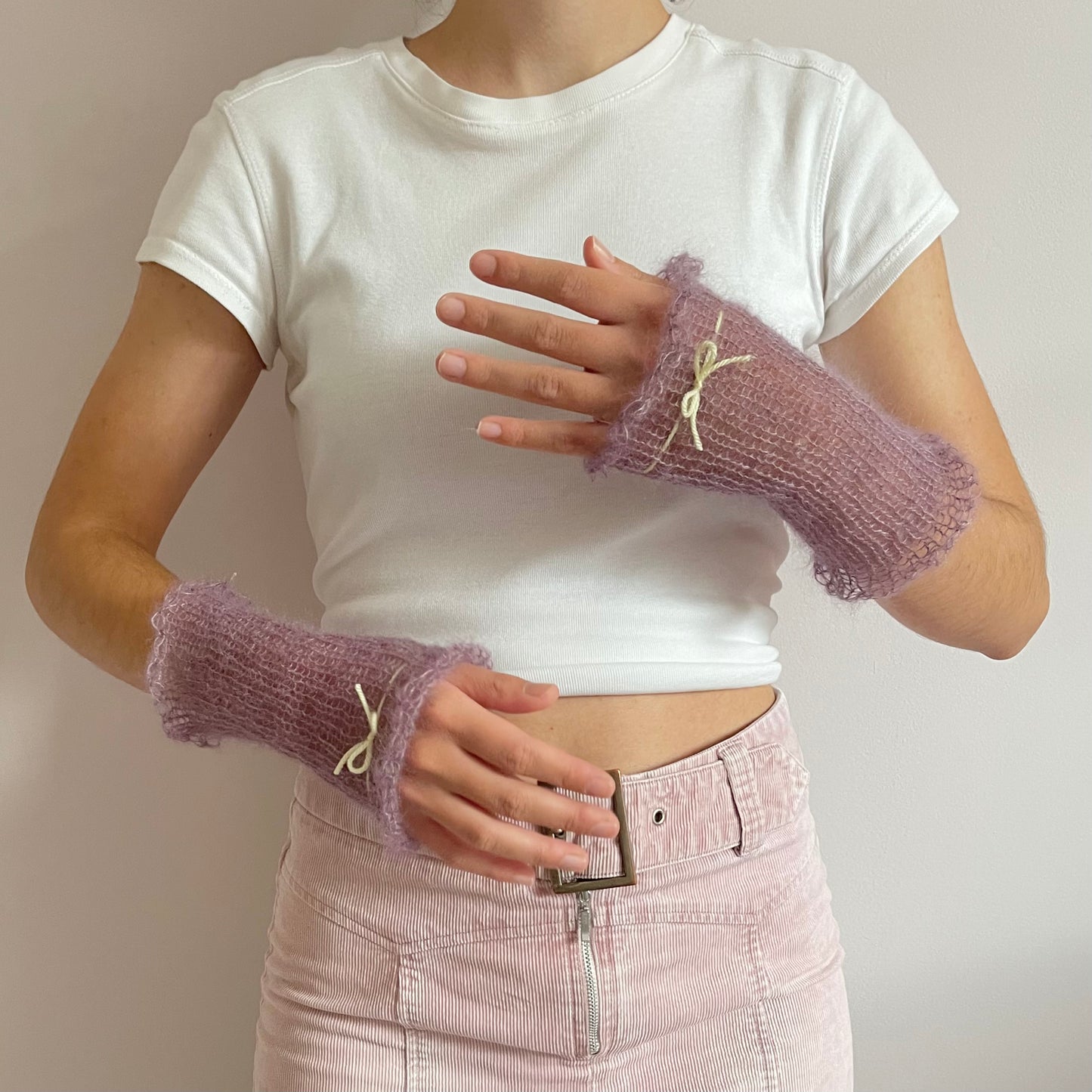 Handmade knitted mohair hand warmers in dusky purple with pastel yellow bow