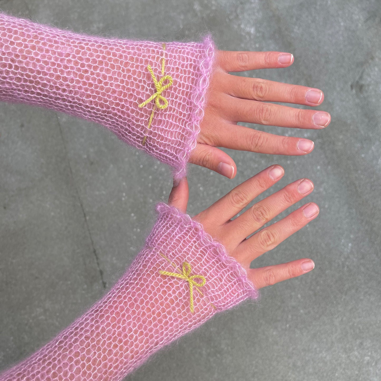 Handmade knitted mohair hand warmers in baby pink with lime green bow