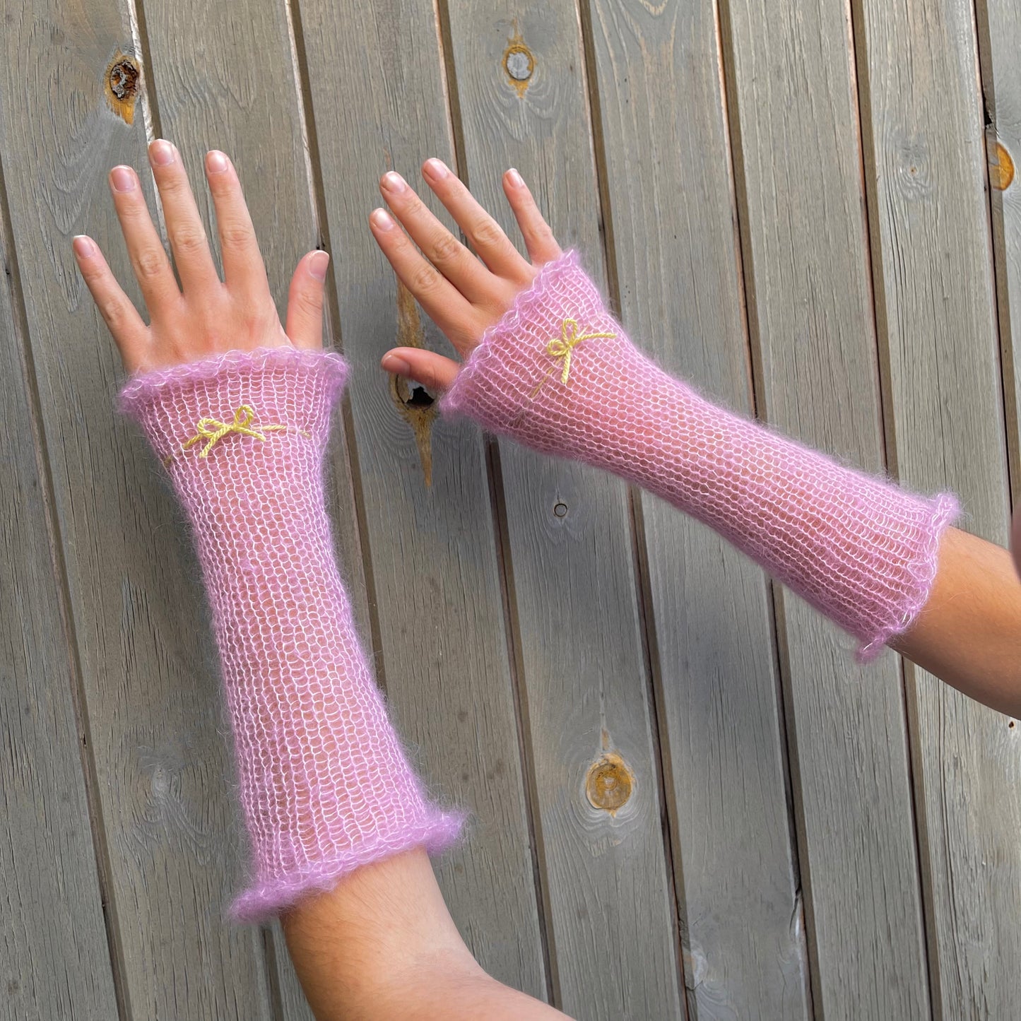 Handmade knitted mohair hand warmers in baby pink with lime green bow
