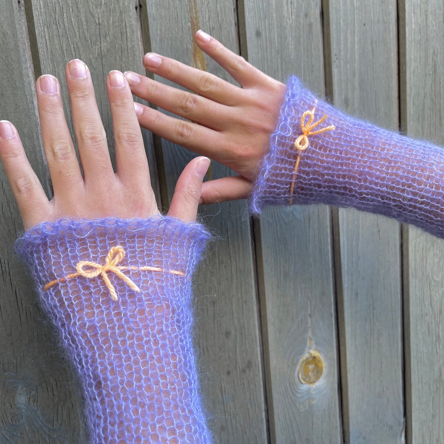 Handmade knitted mohair hand warmers in periwinkle with pastel orange bow